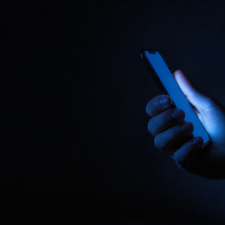 Adolescente usa su teléfono celular de noche, con el rostro iluminado por la pantalla"
