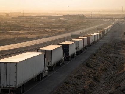 Fila de camiones de carga en una carretera al amanecer rumbo a un cruce fronterizo, en referencia a la relación comercial entre México y Estados Unidos.